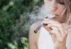 Une femme fume une cigarette électronique