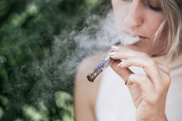 Une femme fume une cigarette électronique