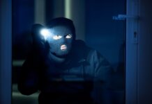 cambrioleur dans une maison avec une lampe