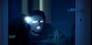 cambrioleur dans une maison avec une lampe
